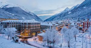 Una ciudad cubierta de nieve con montañas al fondo en Le Cosy Family Lourdes, en Lourdes