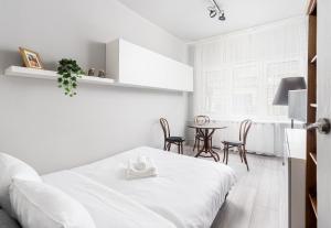een witte slaapkamer met een bed en een tafel bij Wawel Standard Apartment in Krakau