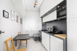 een keuken met witte kasten en een zwart aanrecht bij Wawel Standard Apartment in Krakau