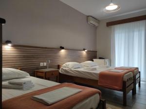 una camera d'albergo con due letti e una finestra di Ενοικιαζόμενα Δωμάτια Ενιπεύς- Rooms Enipeas a Litóchoron