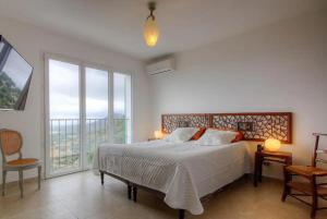 una camera con un letto e una grande finestra di A Casa Praoli - Coin de paradis vue mer ad Aregno
