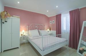 a bedroom with a white bed and pink walls at Dida moj in Senj