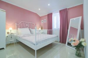 a bedroom with a white bed and pink walls at Dida moj in Senj