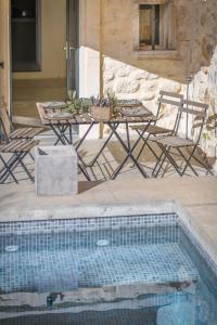 una piscina con tavolo, sedie, tavolo e piscina di L'annexe des Alpilles a Maussane-les-Alpilles