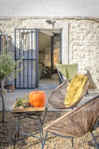 un patio con 2 sedie e un tavolo con un cuscino di L'annexe des Alpilles a Maussane-les-Alpilles Altre 7 foto