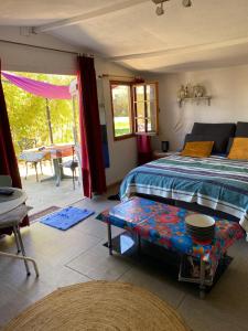 ein Schlafzimmer mit einem Bett und einem Tisch darin in der Unterkunft Chalet des oliviers avec climatisation in Béziers