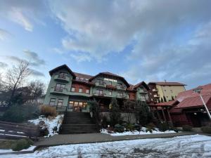 una casa grande con nieve en el suelo en Pensiunea Heveder, en Praid