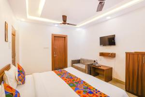 a bedroom with a bed and a chair and a television at FabHotel Duke Inn in Bhopal