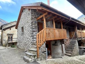 un edificio de piedra con una terraza de madera. en Majagatt Holiday Home en Roveredo