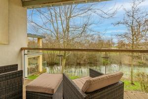 a patio with wicker furniture and a view of a lake at Songthrush in Somerford Keynes