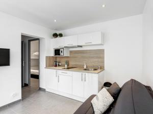 una cocina con armarios blancos y un sofá en una habitación en Modern studio with AC and large terrace on the beach in Cavalaire - Welkeys en Cavalaire-sur-Mer