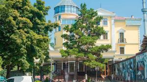 um edifício amarelo com uma árvore em frente em AYKUN Hotel em Almaty