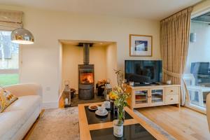 a living room with a couch and a fireplace at Songthrush in Somerford Keynes