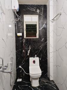 uma casa de banho em mármore preto com um WC e uma janela em Paradise inn em Alandi
