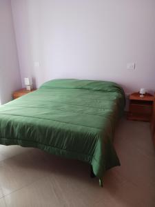 a green bed in a bedroom with two tables at Cappuccini Guest House in San Giovanni in Fiore