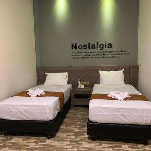 Dos camas en una habitación con dos toallas rosas. en Bless Hotels en Sintang