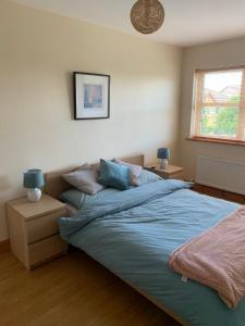 1 dormitorio con cama con sábanas azules y ventana en Tramore Holidays, en Tramore