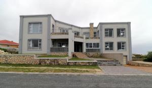 una gran casa blanca con un muro de piedra en Will's Place, en Struisbaai