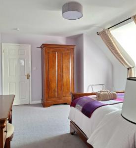 1 dormitorio con 1 cama y armario de madera en Valhalla BnB, en Kenmare