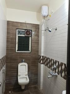 a bathroom with a toilet and a window at Paradise inn in Alandi