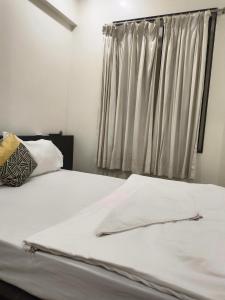 a bedroom with a white bed with a window at Paradise inn in Alandi