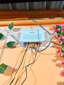 een computer bovenop een tafel met bloemen bij Sweet Home Lodge in Guwahati