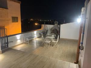 a balcony with chairs and a table at night at Barone luxury rooms in Bari