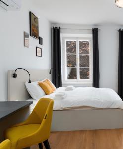 a bedroom with a bed and a desk and a yellow chair at Primus apartments in Ljubljana