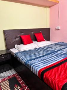a large bed with two red pillows on it at Sweet Home Lodge in Guwahati