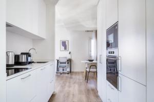 a kitchen with white cabinets and a table and chairs at Renovated La Dreta de lEixample 1br w balcony BCN-89 in Barcelona