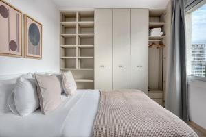 a bedroom with a bed with white cabinets and a window at Blueground Pedralbes furnished BCN-92 in Barcelona