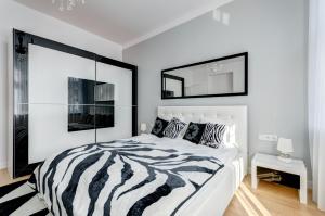 a zebra print bed in a white bedroom with a mirror at Platinum Residence - Chmielewskiego in Sopot