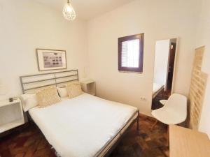 een slaapkamer met een bed, een stoel en een raam bij Hostal Café FRENTEABASTOS in Carmona