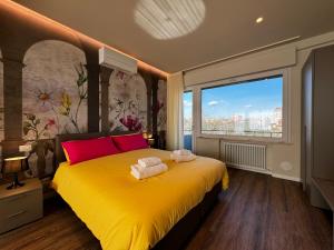 una camera da letto con un letto giallo con cuscini rossi e una finestra di SKYLINE- 3 Apartments with view a Siena