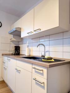 - une cuisine avec des placards blancs et un évier dans l'établissement Schönes 1-Zimmer-Appartement, Büsum (4km) Nordsee, à Oesterdeichstrich