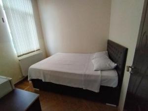 um pequeno quarto com uma cama com lençóis brancos e almofadas em BK GOLD HOTEL em Batumi