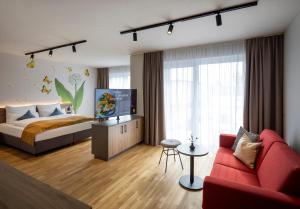 ein Schlafzimmer mit einem Bett und einem roten Sofa in der Unterkunft JUFA Hotel Bad Radkersburg - inkl 4h Thermeneintritt in Bad Radkersburg