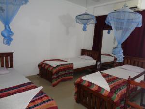 a room with three beds and a mirror at Saranga Holiday Inn in Wellawaya