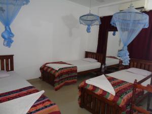 Cette chambre comprend 3 lits et un miroir. dans l'établissement Saranga Holiday Inn, à Wellawaya