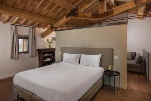 a bedroom with a large white bed and a couch at Dimora storica Torre dei Petricci 12 in Sovicille