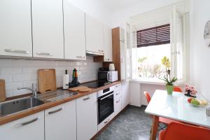 cocina con armarios blancos, fregadero y mesa en Apartment Anka, en Opatija