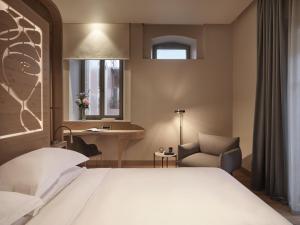 a bedroom with a bed and a chair and a window at Domus Blanc Boutique Hotel in Chania