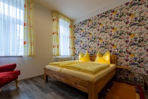 1 dormitorio con cama con almohadas amarillas y pared de flores en Ferienwohnung - Blumenstraße en Sebnitz