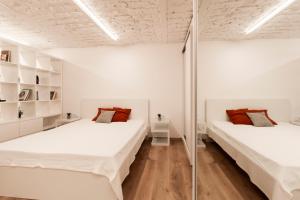 ブダペストにあるHeart of Budapest Apartmentの白い壁とウッドフロアの客室で、ベッド2台が備わります。