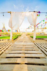 a wooden walkway with a white tent and flags at Ruby Star Quỳnh Resort 