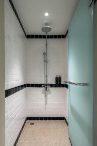 a bathroom with a shower with black and white tiles at The Cotton Saladaeng Hotel in Bangkok