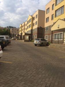 Azure Skyline Villa, 3BR Modern Condo Nakuru City. في ناكورو: موقف للسيارات مع وقوف السيارات أمام المباني