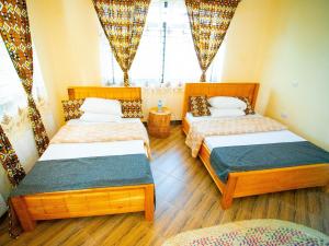 a room with three beds and a window at Materuni Homes in Moshi