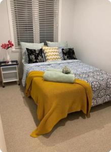 a bedroom with a bed with a yellow blanket on it at Auckland Airport apartment in Auckland