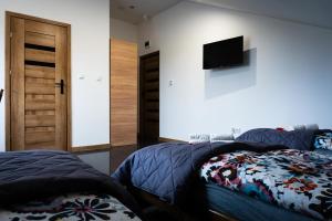 a bedroom with two beds and a television on the wall at KR Pokoje in Tokarnia